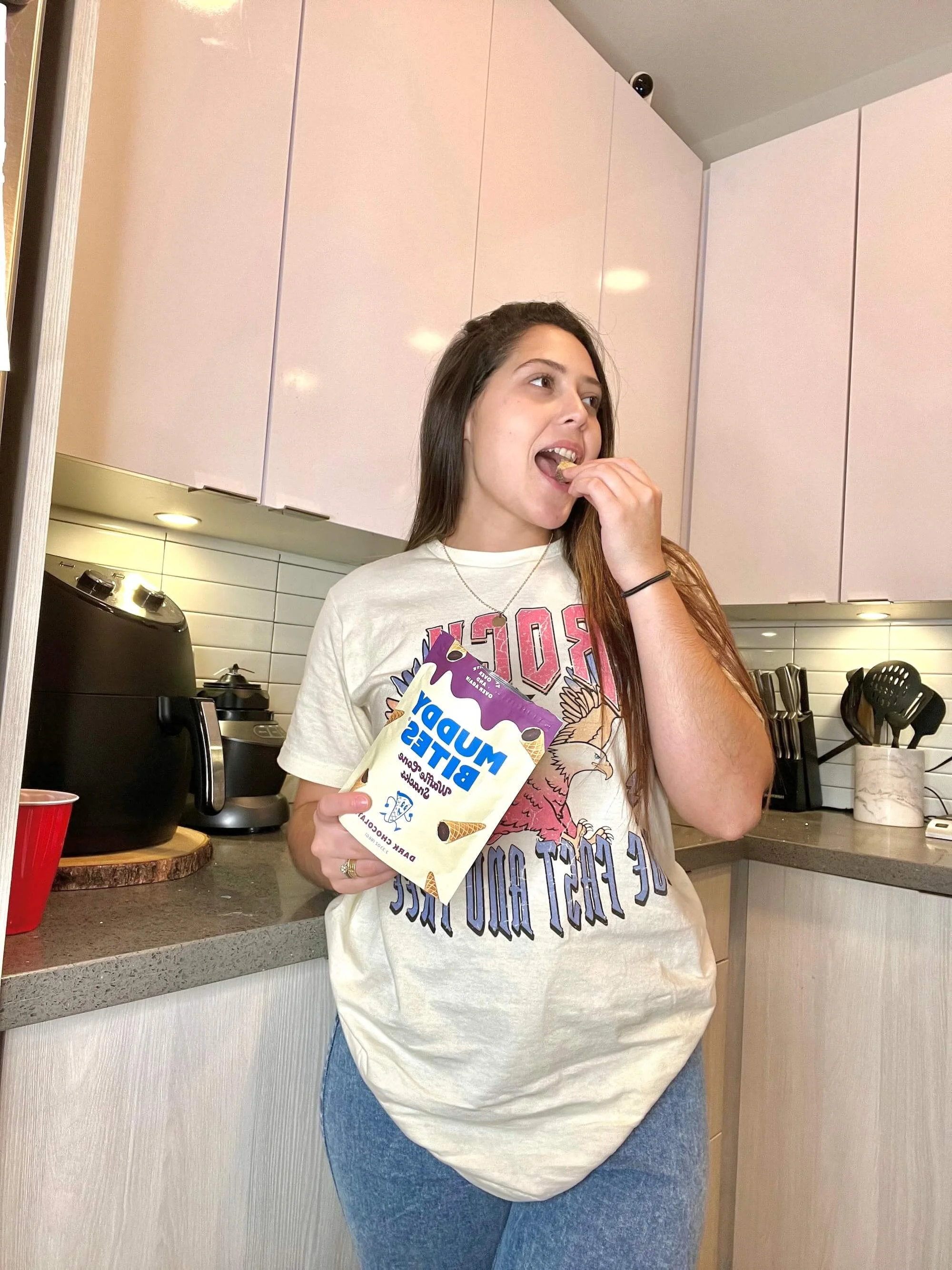 A woman in a kitchen snacking on Muddy Bites