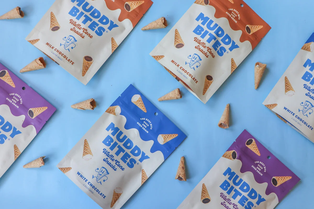 Muddy Bites bags scattered with waffle cones on blue